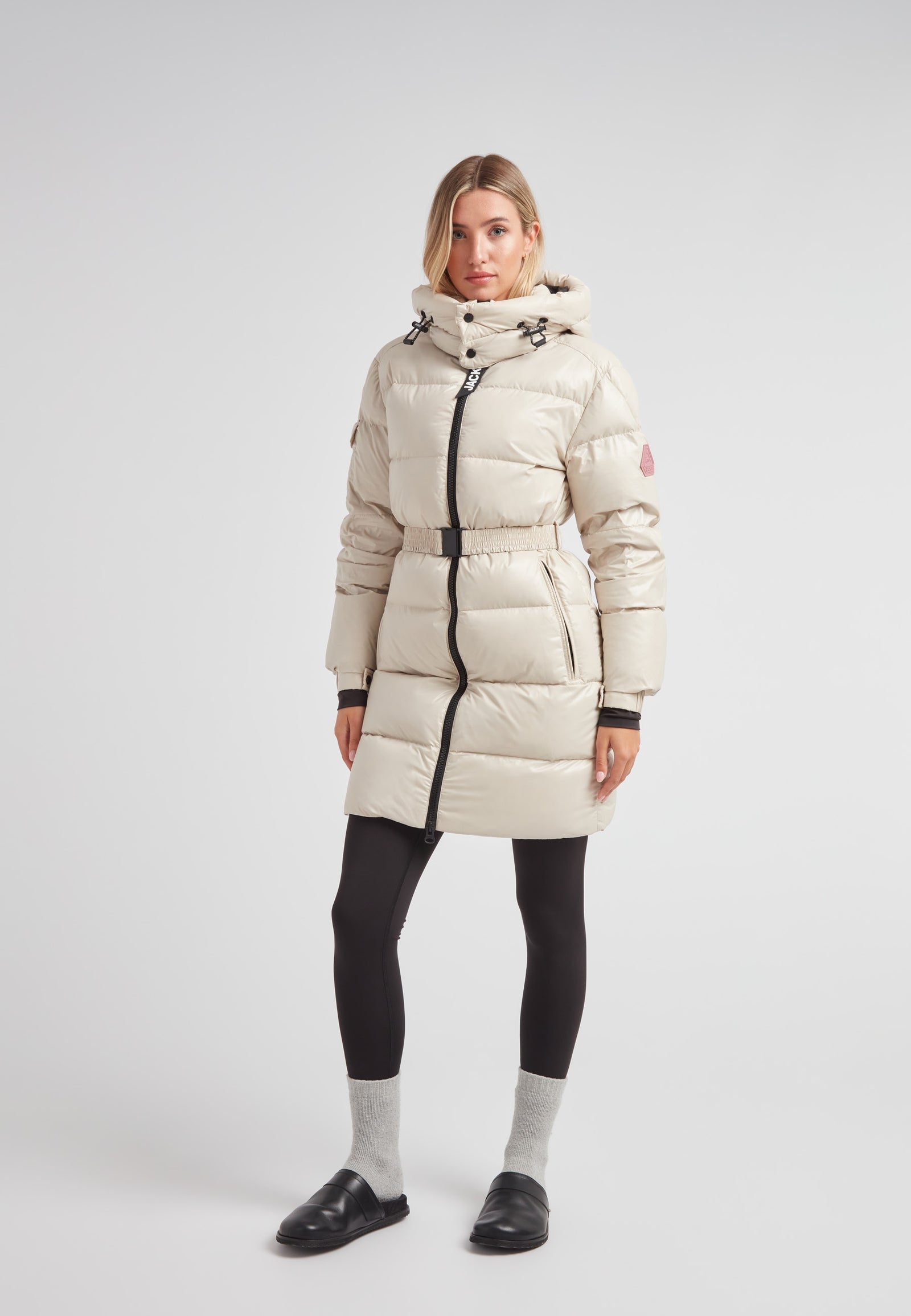 EZ Belted Down Puffer Coat Lux Stone worn by a woman, showcasing its stylish design and cozy insulation.