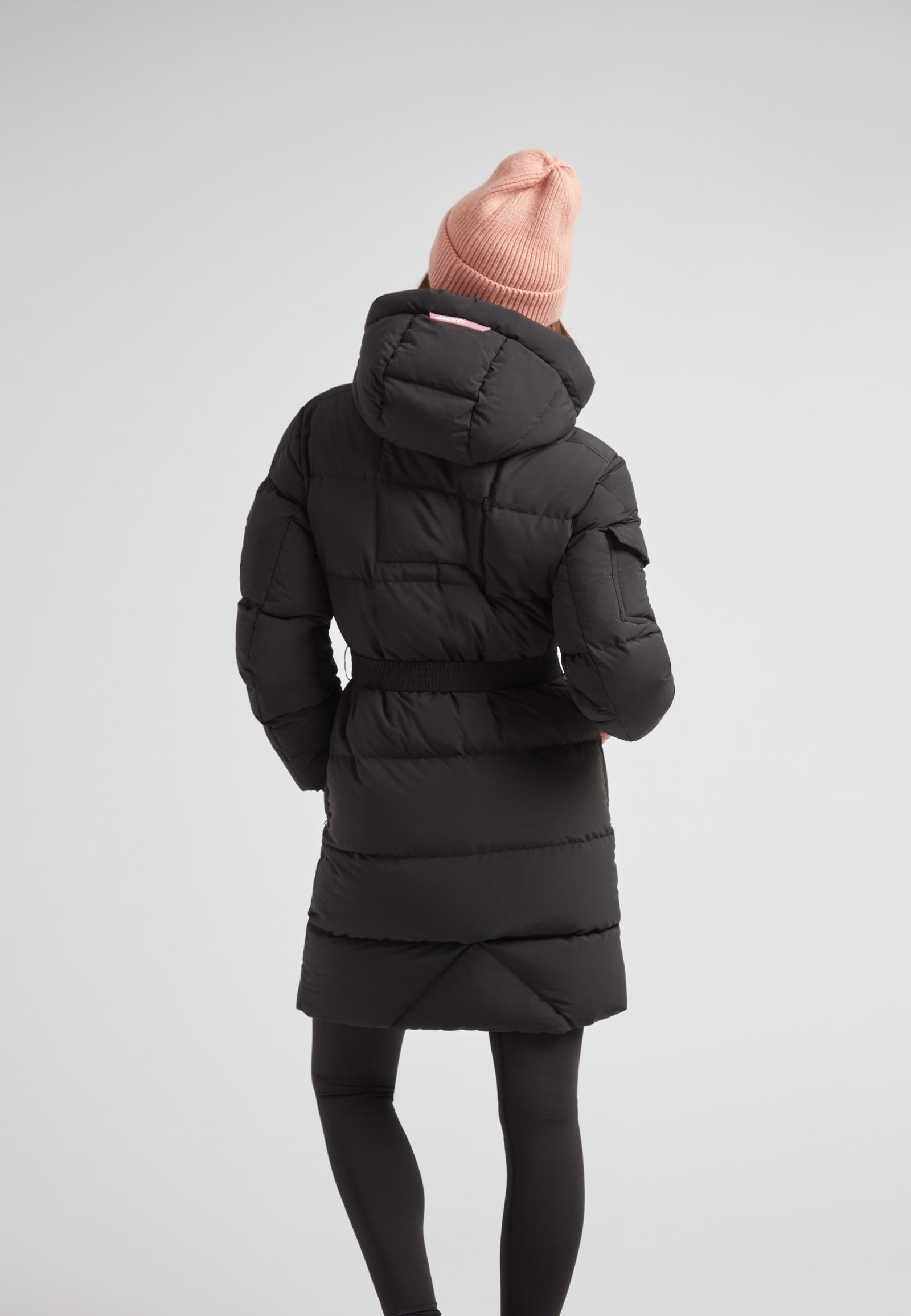 Model wearing the EZ Belted Down Puffer Coat Matt Black with a pink beanie from the back.