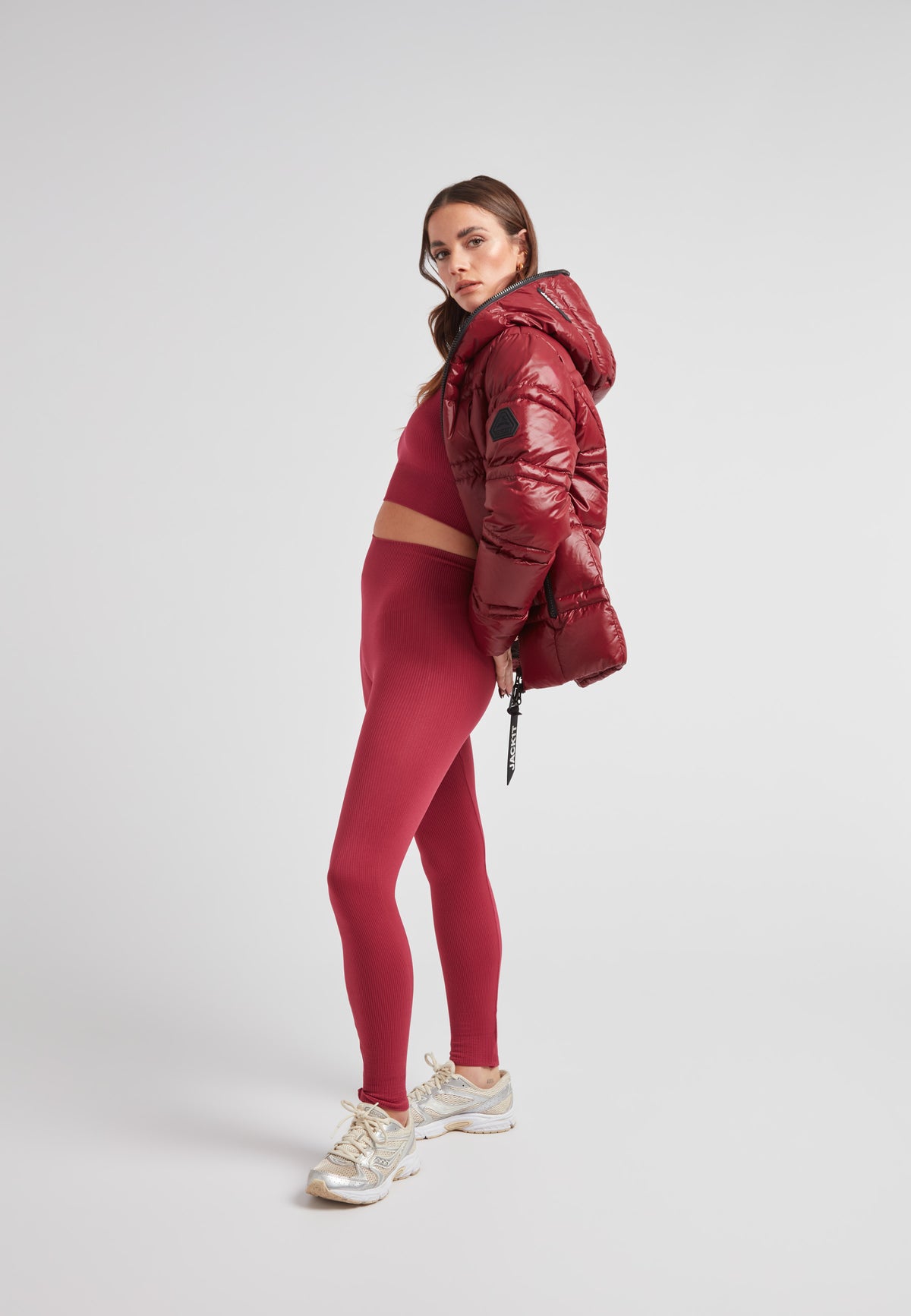 Model wearing R4D Tramline Puffer Racer Jacket Lux Cranberry with matching leggings and sneakers.