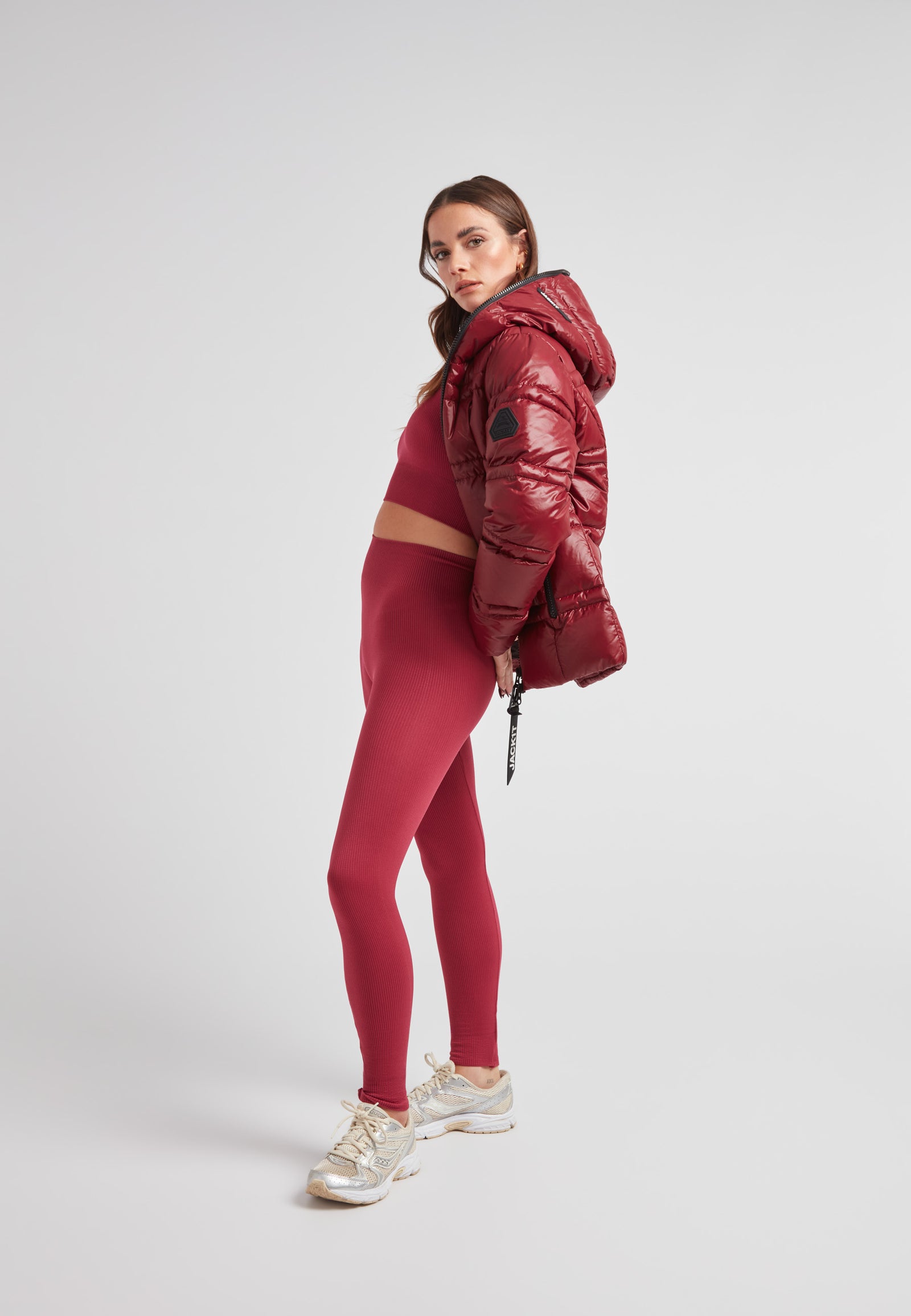 Model wearing R4D Tramline Puffer Racer Jacket Lux Cranberry with matching leggings and sneakers.