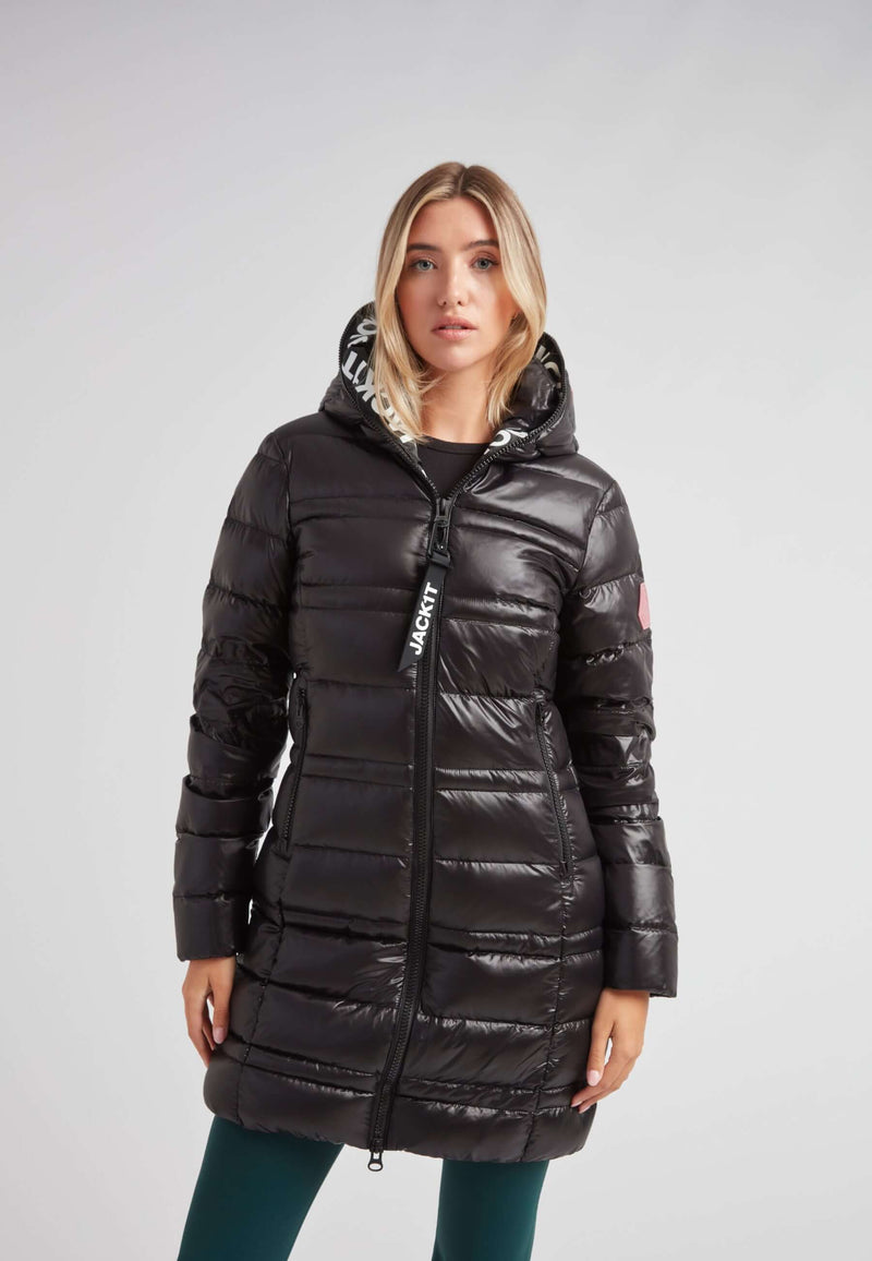 Woman wearing the R4D Tramline Down Coat Lux Black with hood, showcasing its sleek design and style.