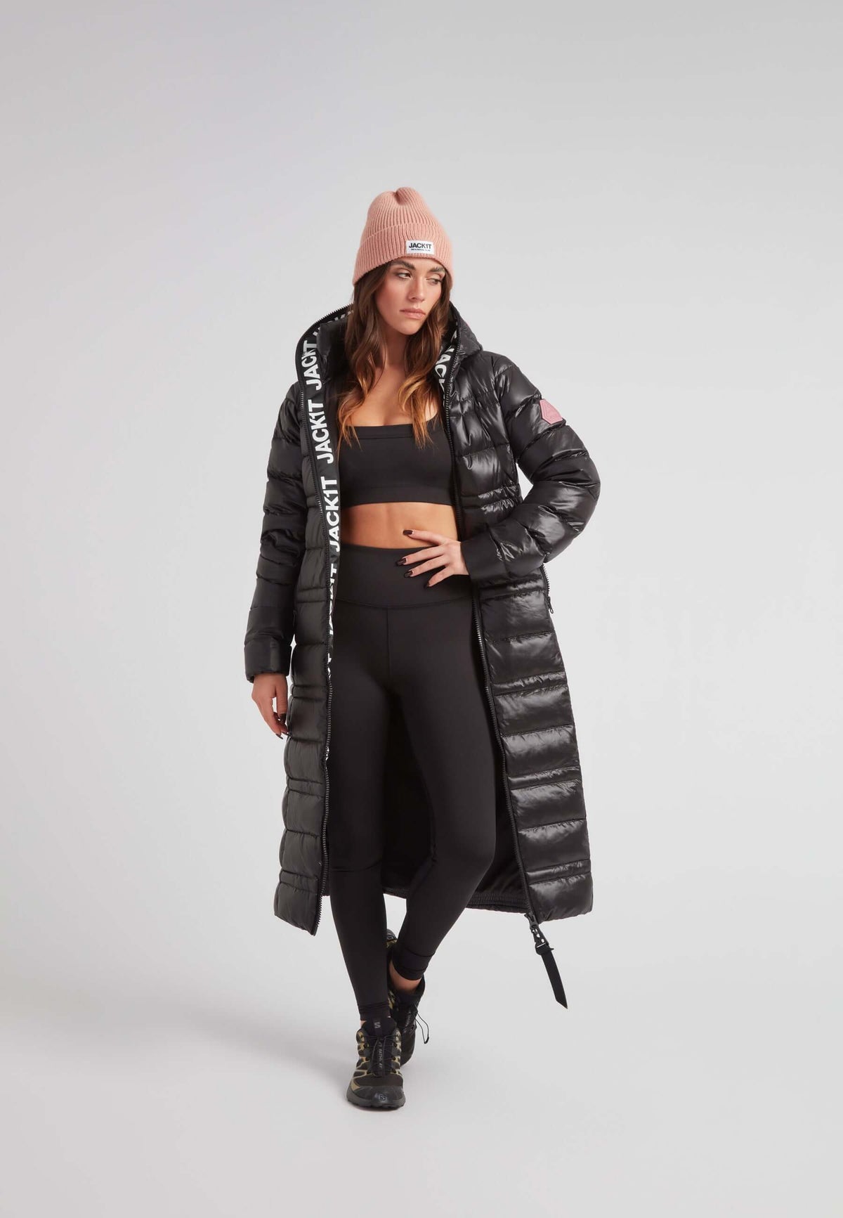 R4D Tramline Extra Long Down Coat Lux Black with hood and side zip, worn by model in black leggings and pink beanie.