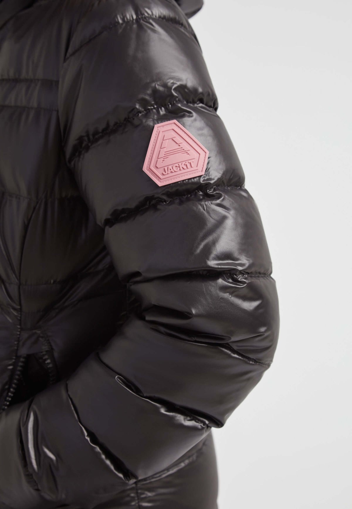 R4D Tramline Extra Long Down Coat Lux Black featuring a shiny black shell and a pink badge on the sleeve.