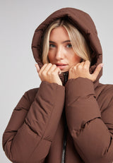 Model wearing the Black Star Extra Long Down Coat Matt Mid Brown with a hood, showcasing its warm design and stylish look.
