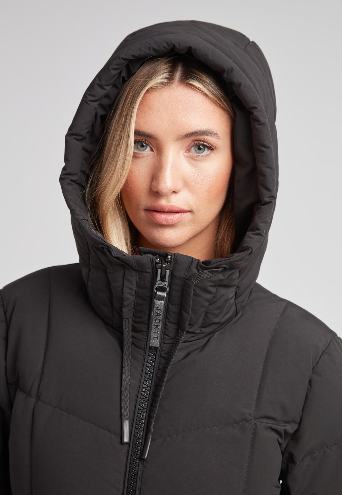 Woman wearing the Black Star Extra Long Down Coat Matt Black with adjustable hood.