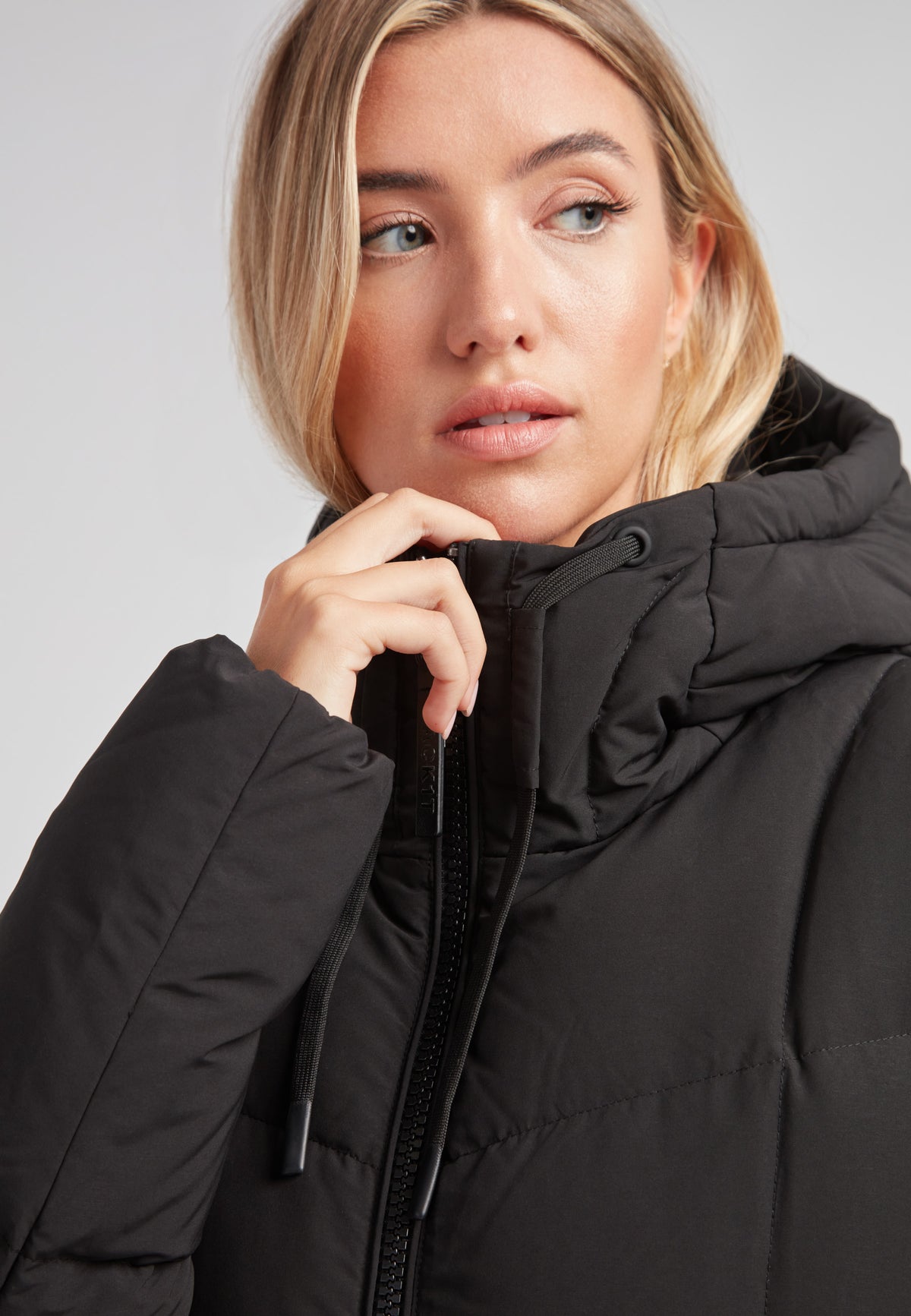 Close-up of a model wearing the Black Star Extra Long Down Coat Matt Black with an adjustable hood.