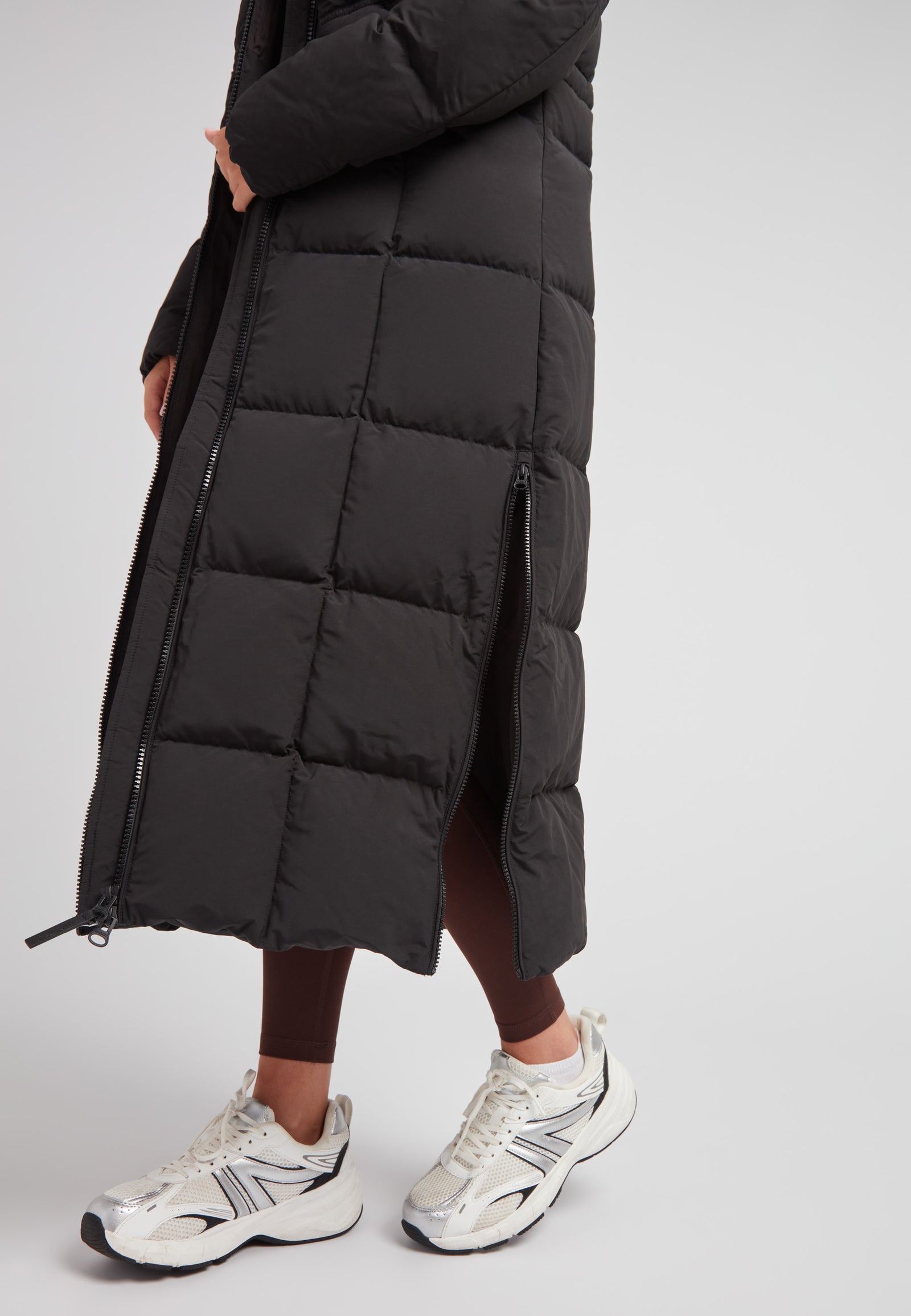 Black Star Extra Long Down Coat Matt Black showcased with sleek design and stylish silver sneakers.
