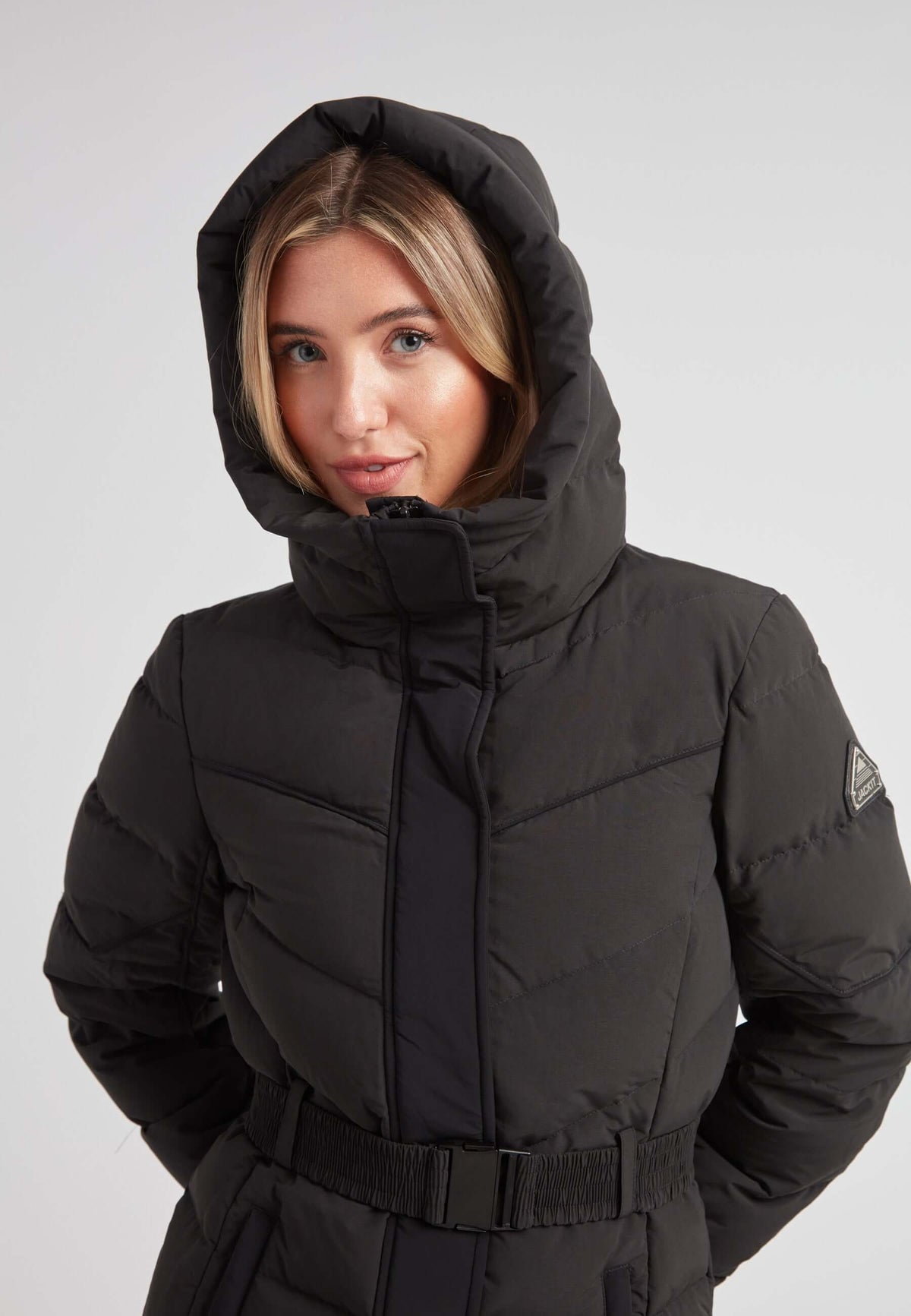 Woman wearing the Diamond Belted Down Coat Matt Black with a stylish hood, showcasing its refined winter design.