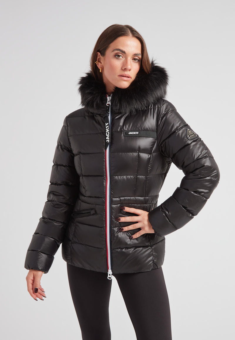 Black racer puffer jacket with fur hood worn by a model, showcasing alpine style and warmth.
