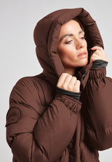 Cocoon Ultra Long Down Coat Mid Brown showcasing its oversized silhouette and cozy hood.