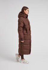 Cocoon Ultra Long Down Coat Mid Brown worn by model, showcasing its oversized silhouette and hood.