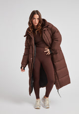 Cocoon Ultra Long Down Coat Mid Brown displayed by a model wearing matching brown attire.