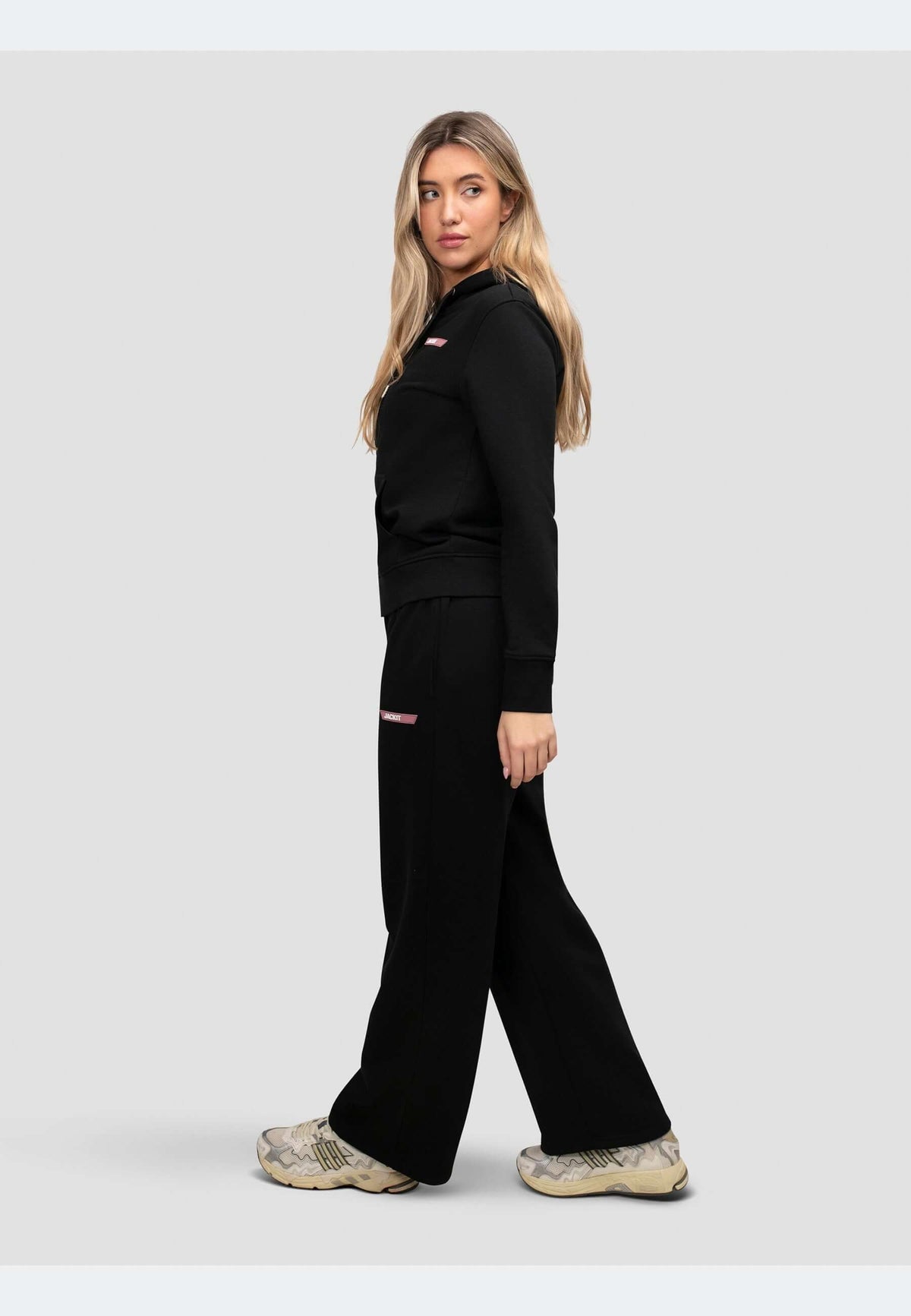 Model wearing a zip through black hoodie with relaxed fit and matching pants, showcasing a sporty look.