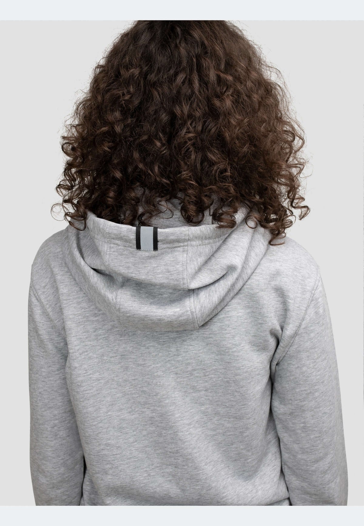 Back view of a person wearing a grey hoodie with curly hair, showcasing the hood and neck detailing.