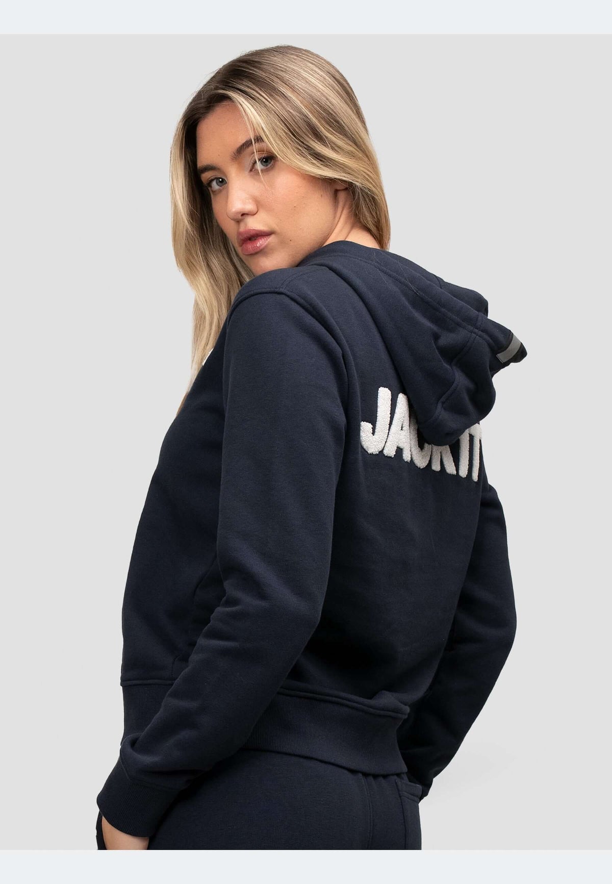 Woman wearing a navy hoodie showcasing the back logo in a relaxed fit, perfect for everyday comfort.