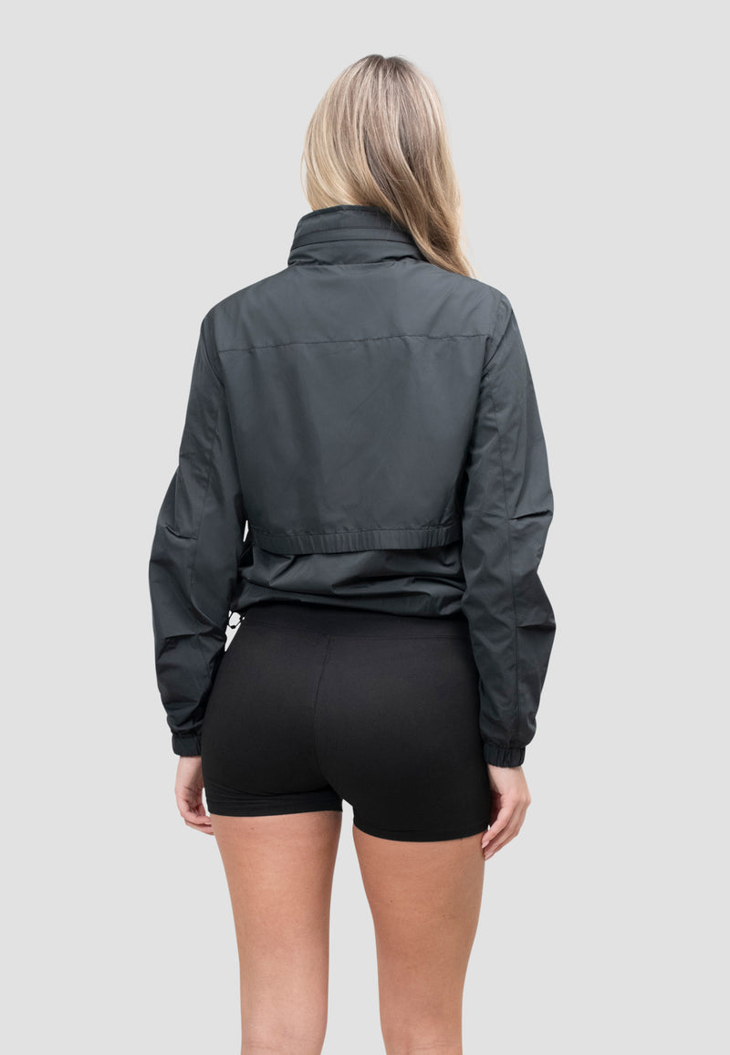 Back view of a woman wearing a lightweight women's black windbreaker. Perfect for spring and summer weather.