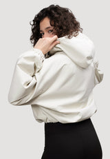 A model showcasing the Women's Cream Cropped Jacket from the back, featuring a hood and relaxed fit.