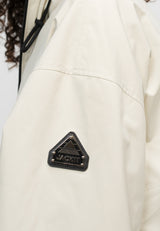 Close-up of the sleeve of a women's cream cropped jacket featuring a black logo patch.