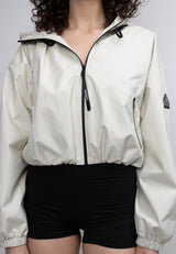 Model wearing Women's Cream Cropped Jacket, a lightweight windbreaker, paired with black shorts.