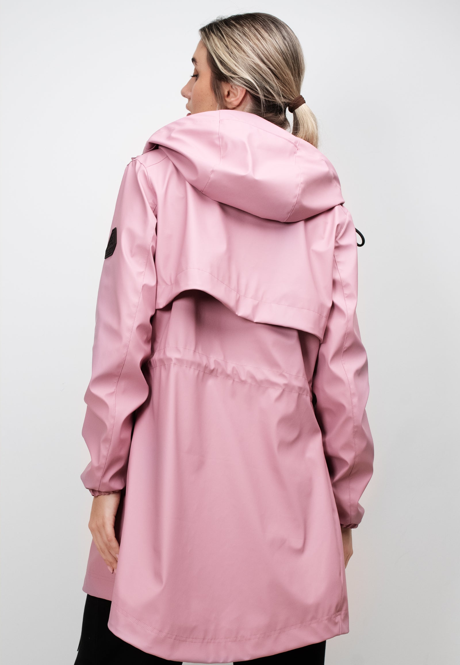 Back view of a woman wearing a lightweight women's pink raincoat with cape in dusty pink.