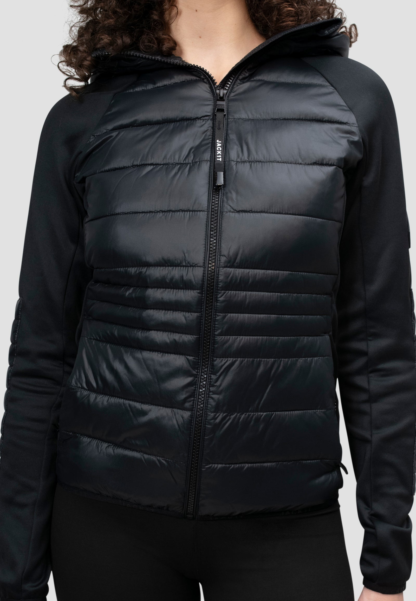 Model wearing a women's black hooded jacket with a sleek design and lightweight insulation for comfort.