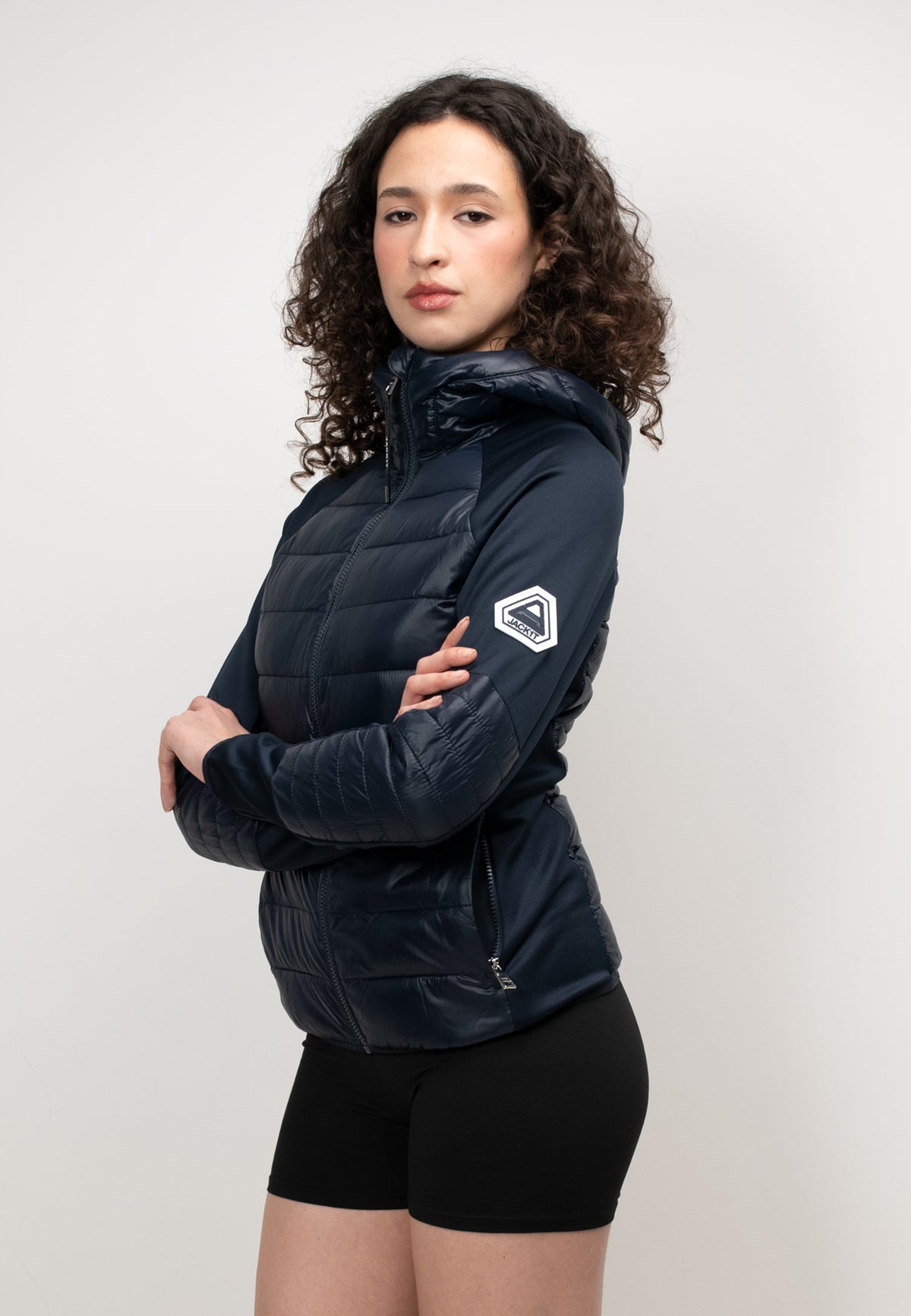 Model wearing a women's navy hooded jacket with a slim fit, showcasing its lightweight, water-resistant fabric.