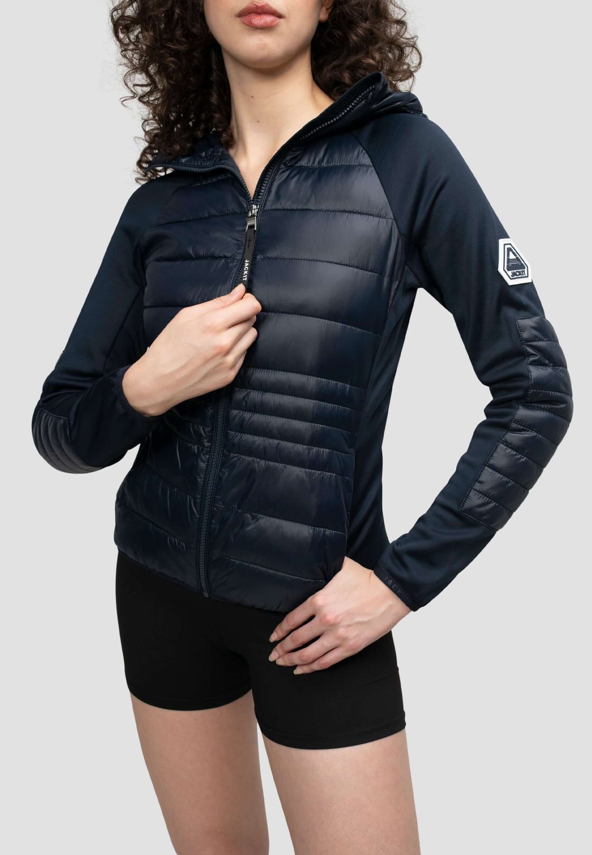 Model wearing a women's navy hooded jacket with lightweight water resistant fabric and a slim fit.