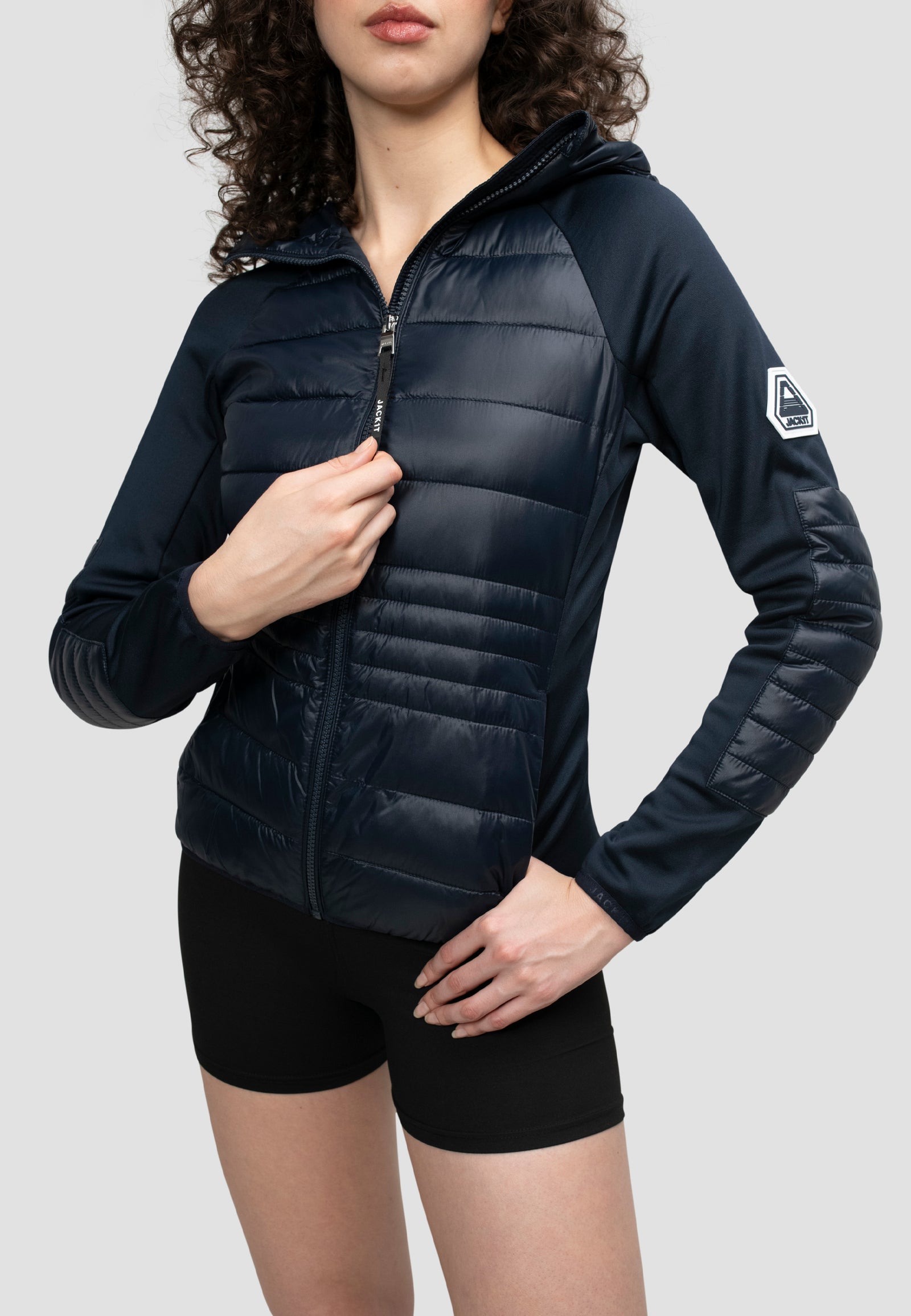 Model wearing a women's navy hooded jacket with lightweight water resistant fabric and a slim fit.