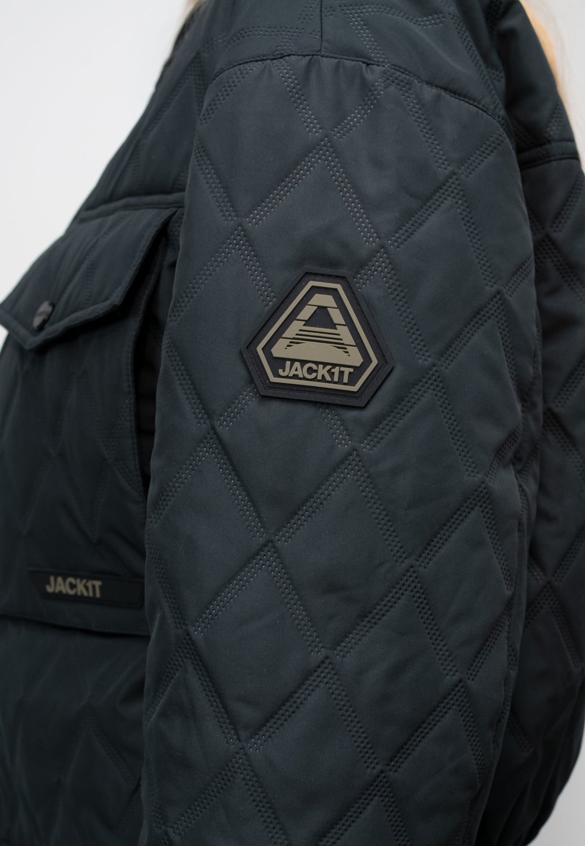 Close-up of the women's black quilted shirt jacket showing the diamond pattern and logo detail.