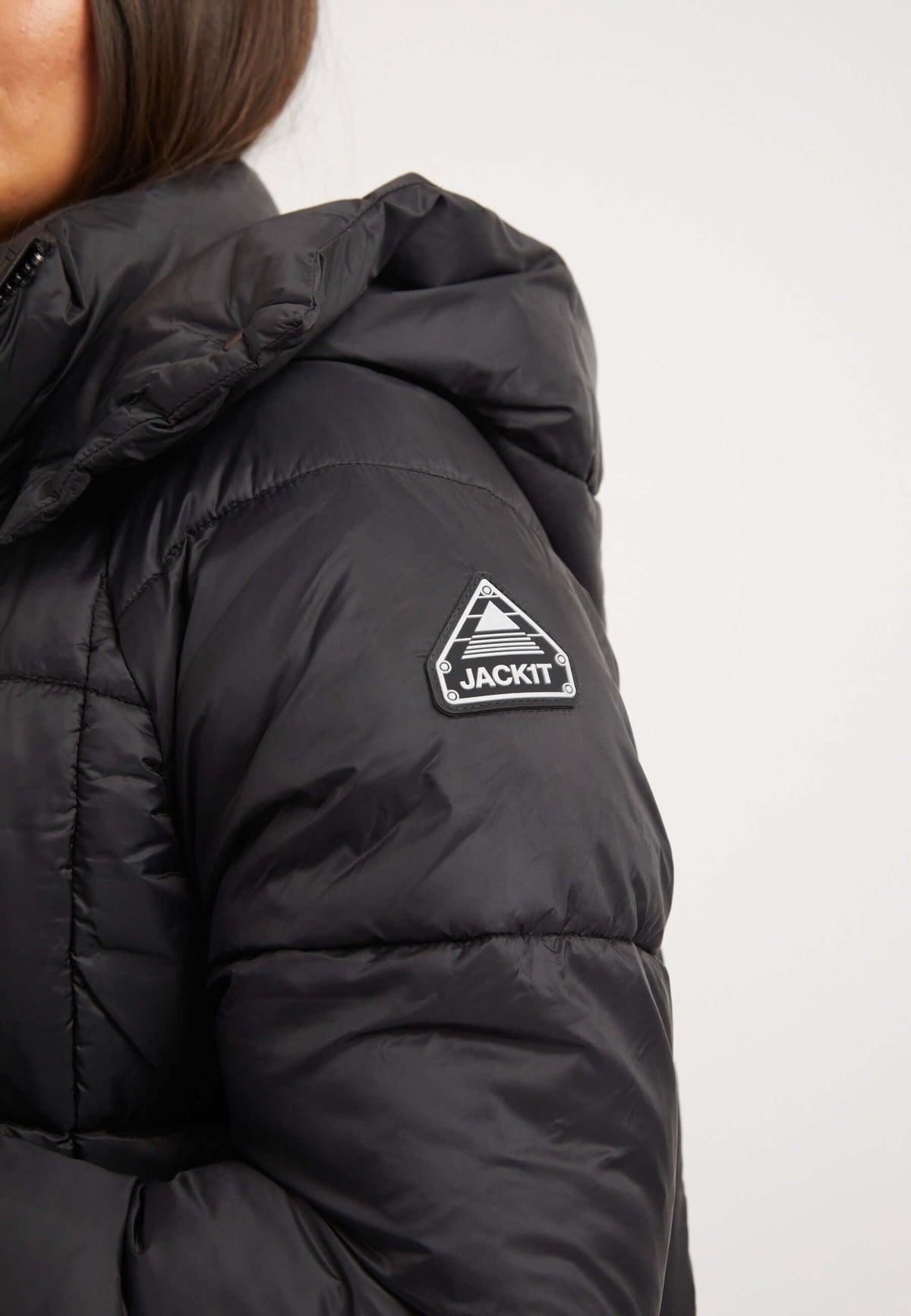 Close-up of a woman wearing the womens black puffer jacket with a reflective badge on the shoulder.