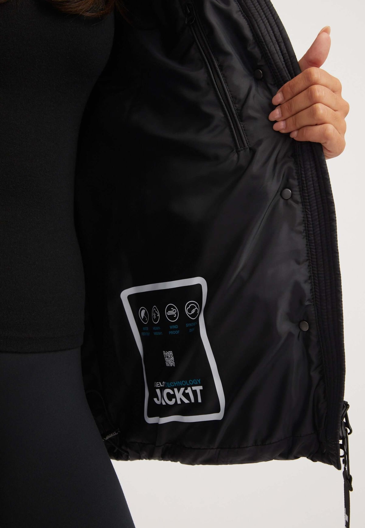 Close-up of the interior label of a womens black puffer jacket, featuring care instructions and fabric details.
