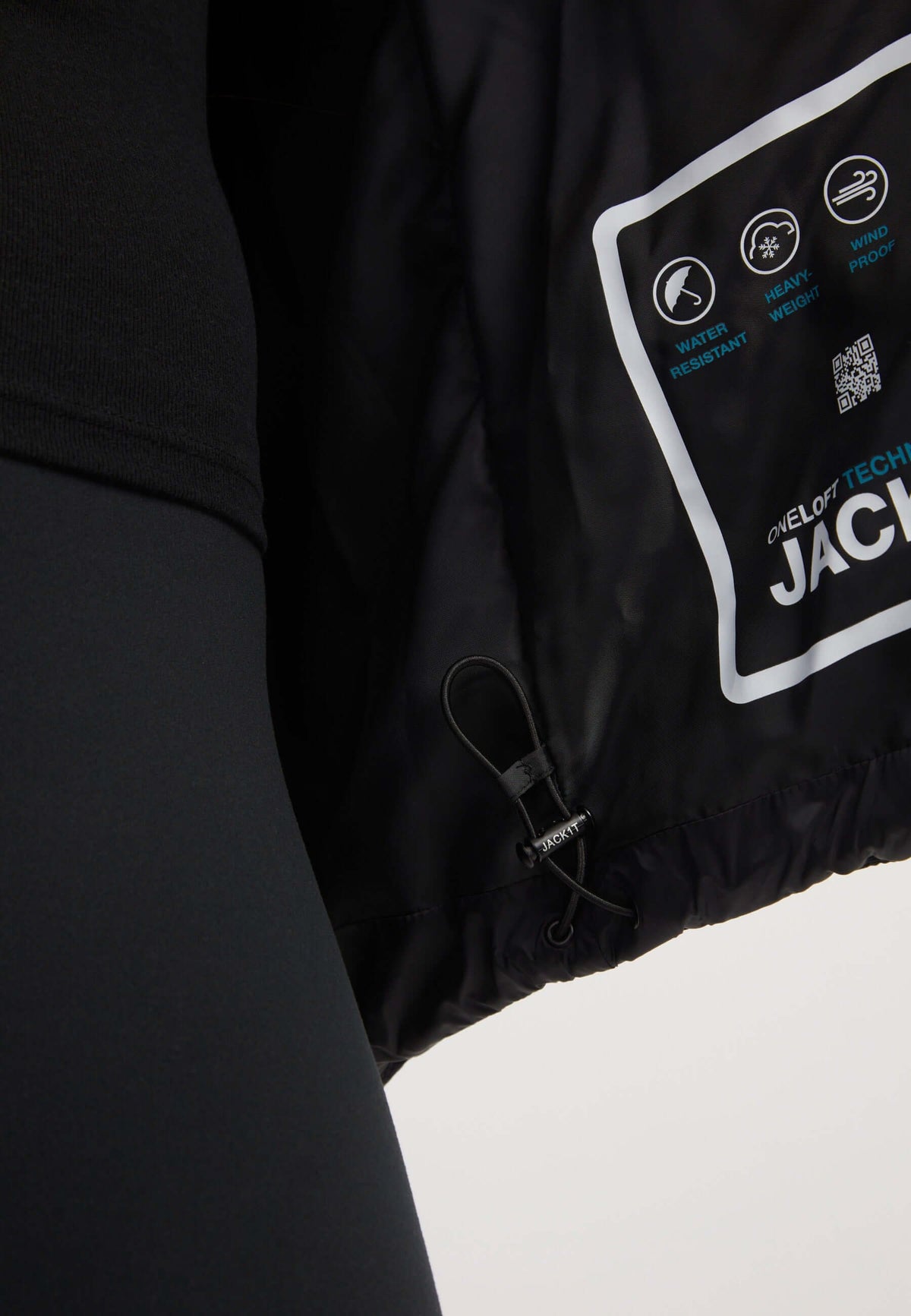 Close-up of the interior of a womens black puffer jacket showcasing tags and features.