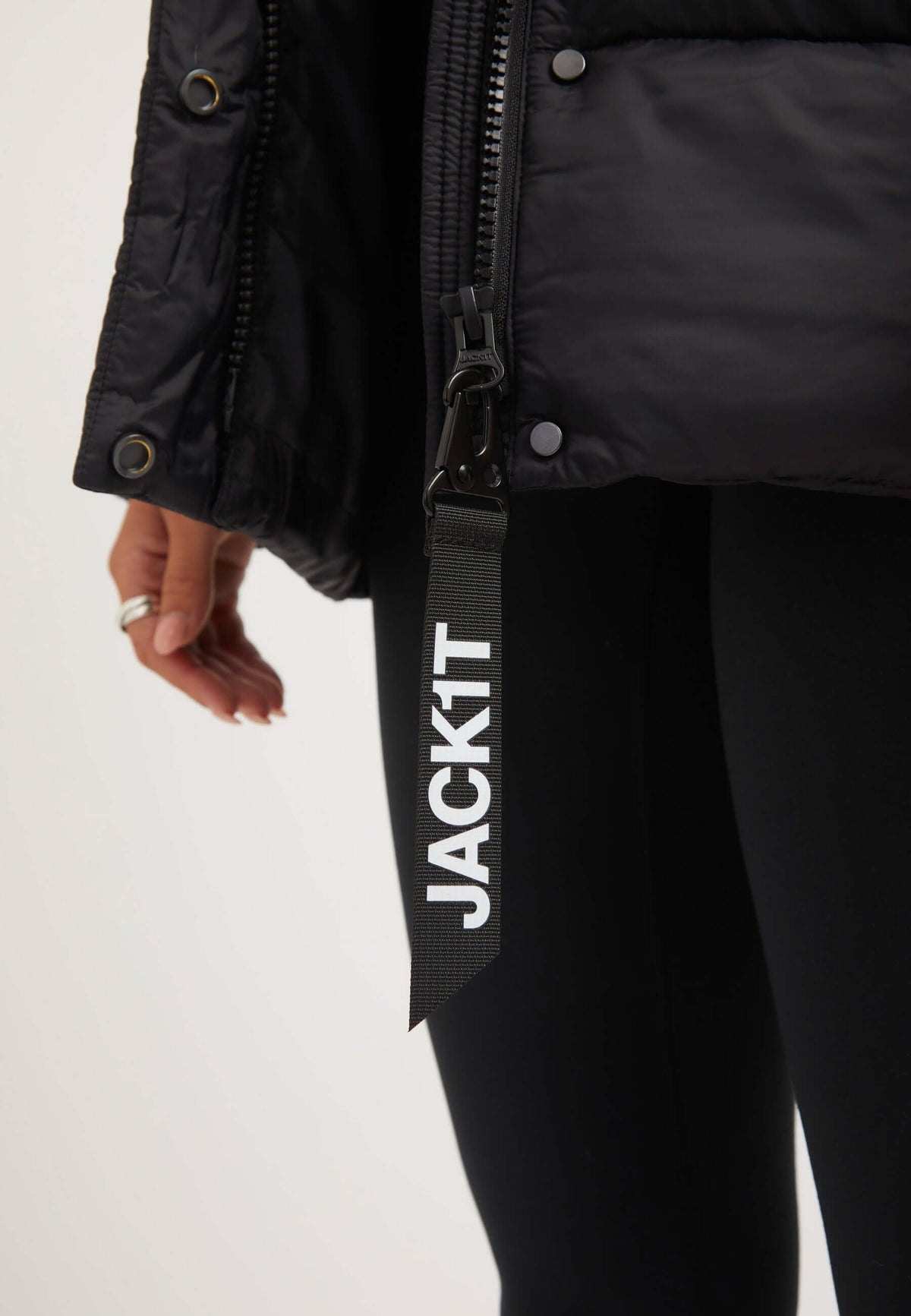 Close-up of a womens black puffer jacket showcasing the zipper and branded tag detail.