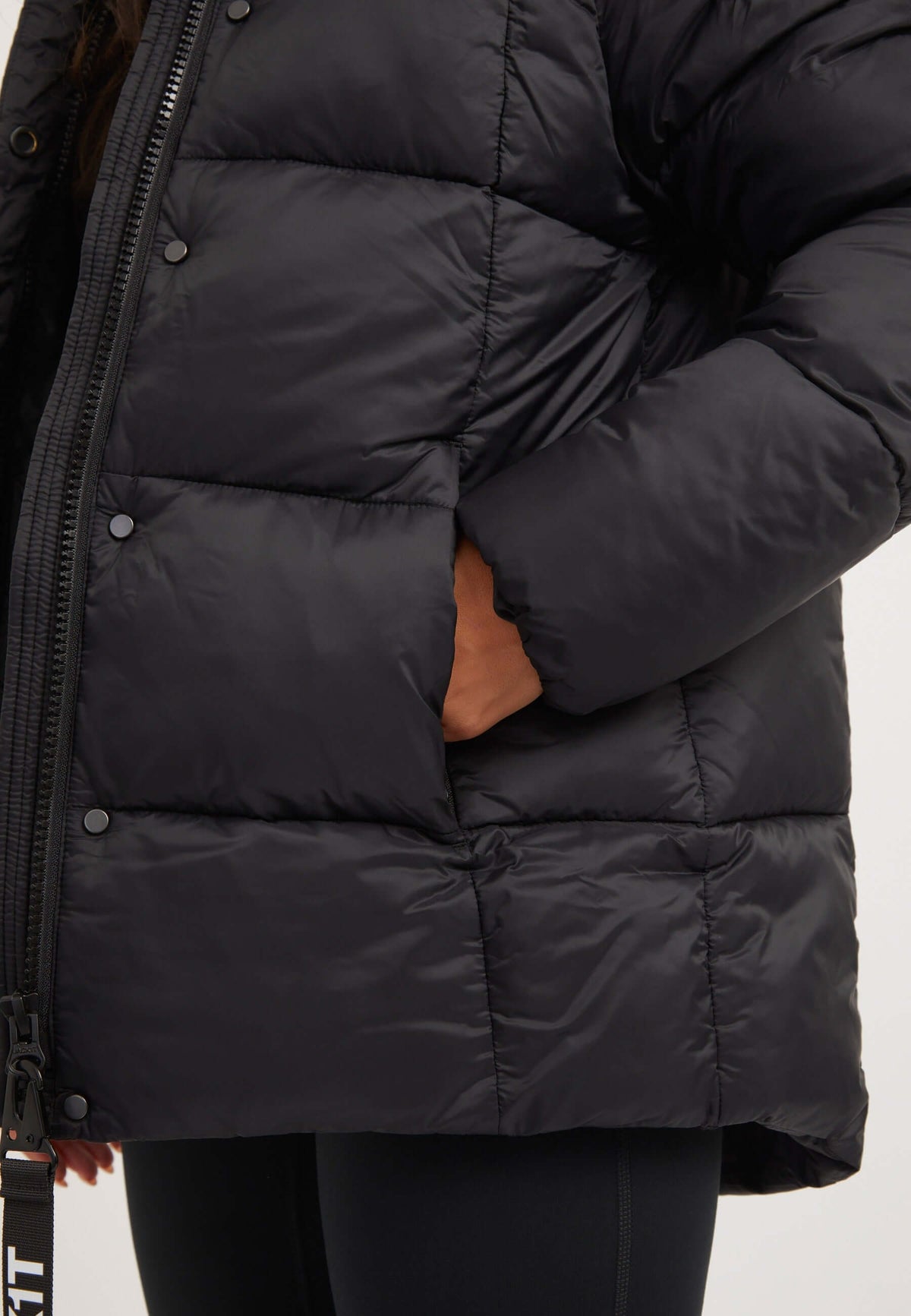 Close-up of a woman wearing a womens black puffer jacket with visible side pocket and lightweight design.