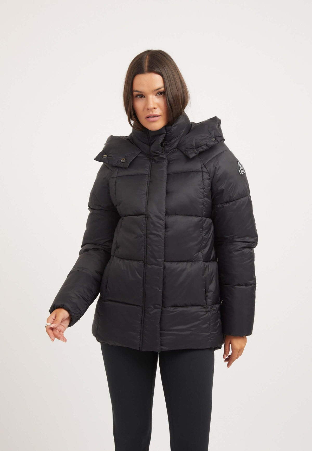 Womens black puffer jacket featuring tapered design, adjustable hood, and durable water-repellent fabric.