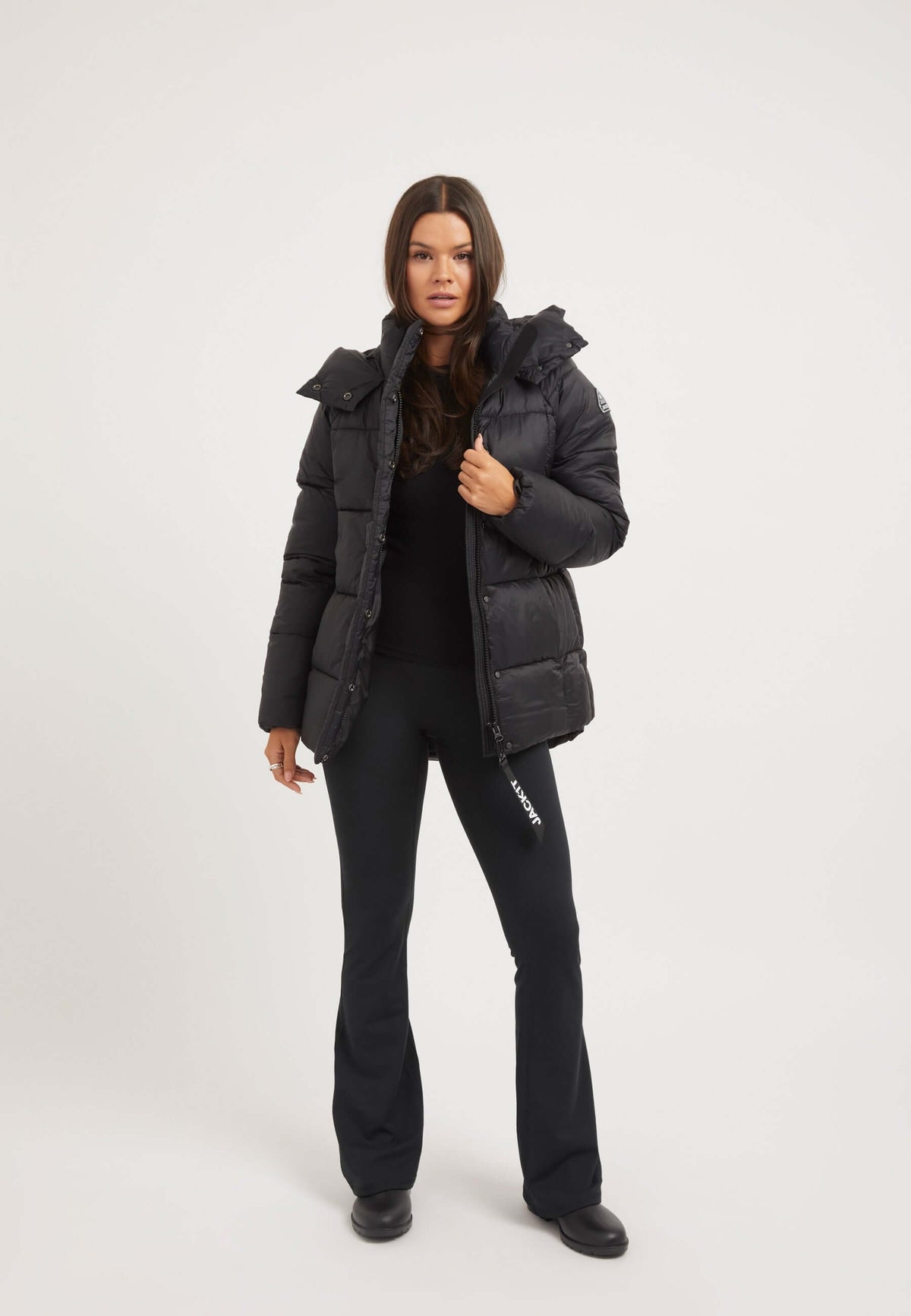 Model wearing the womens black puffer jacket featuring a tapered fit and adjustable hood.