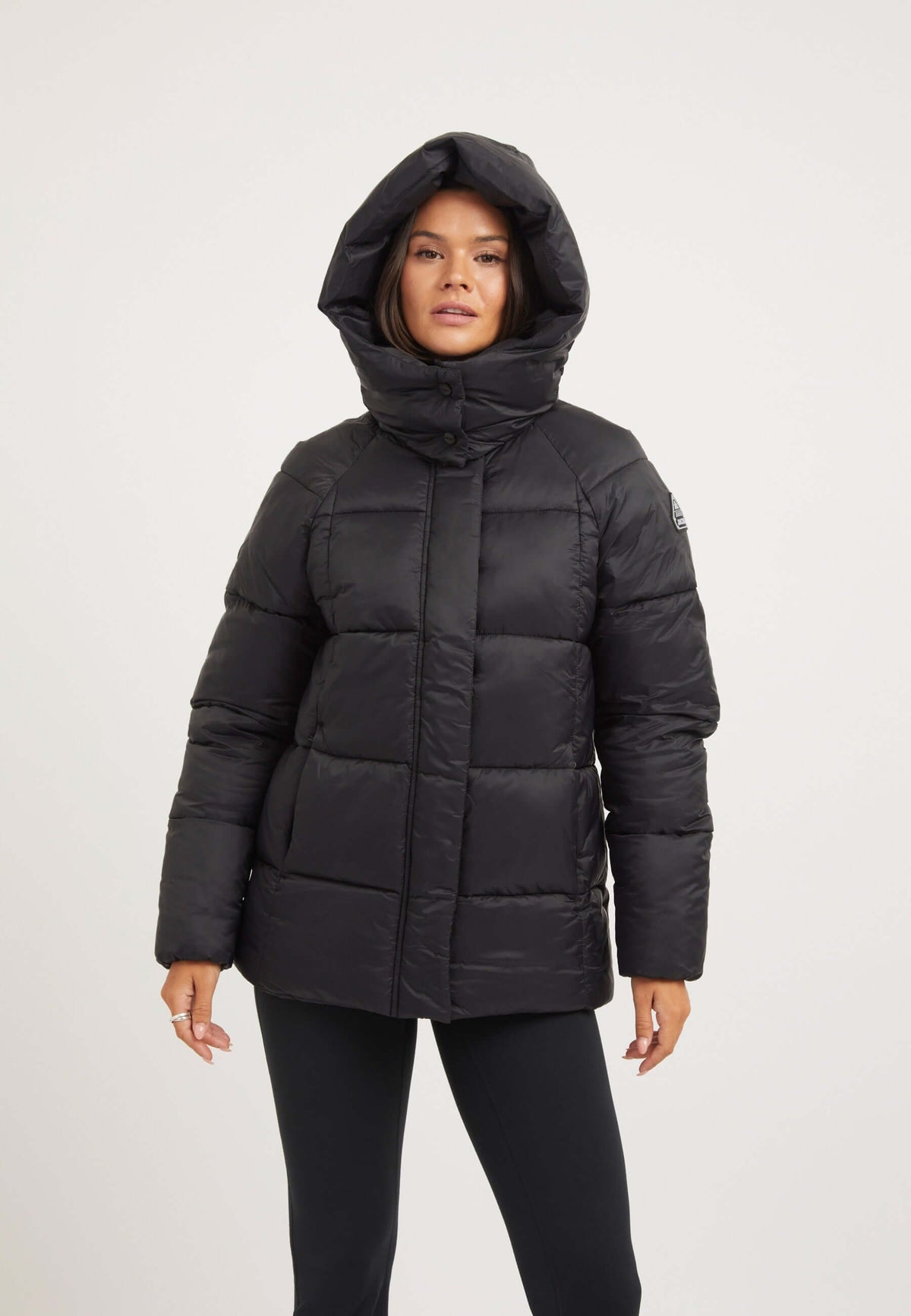 Womens black puffer jacket with adjustable hood and tapered fit, ideal for cold weather protection.