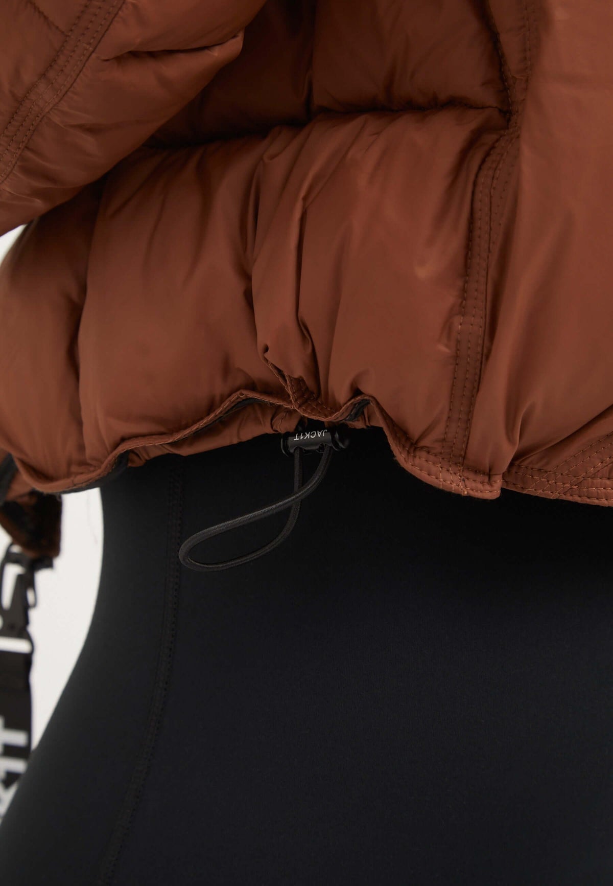 Close-up of Cloud Boss Jacket Mocha Brown showcasing the elastic waistband detail of the Womens Puffer Jacket Brown.