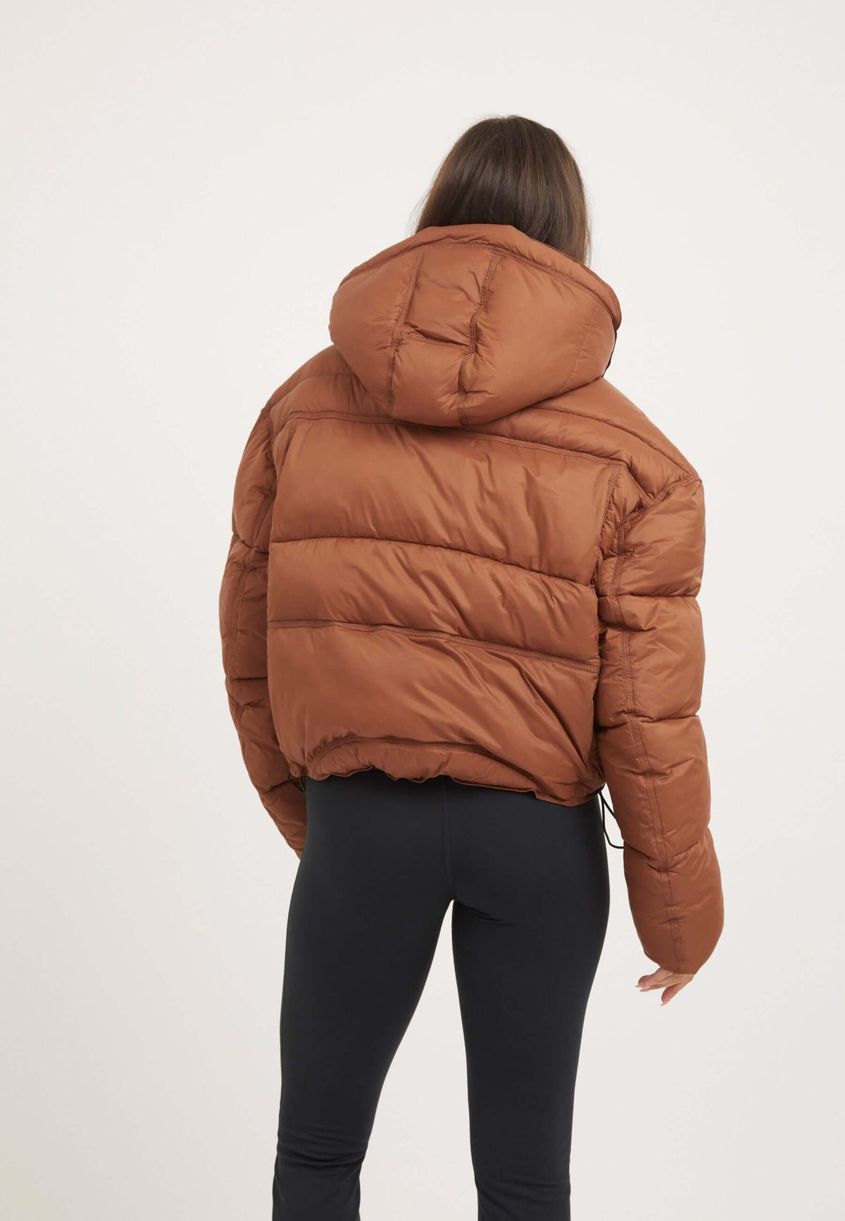 Womens Puffer Jacket Brown displayed from the back, showcasing its oversized drop shoulder silhouette and removable hood.