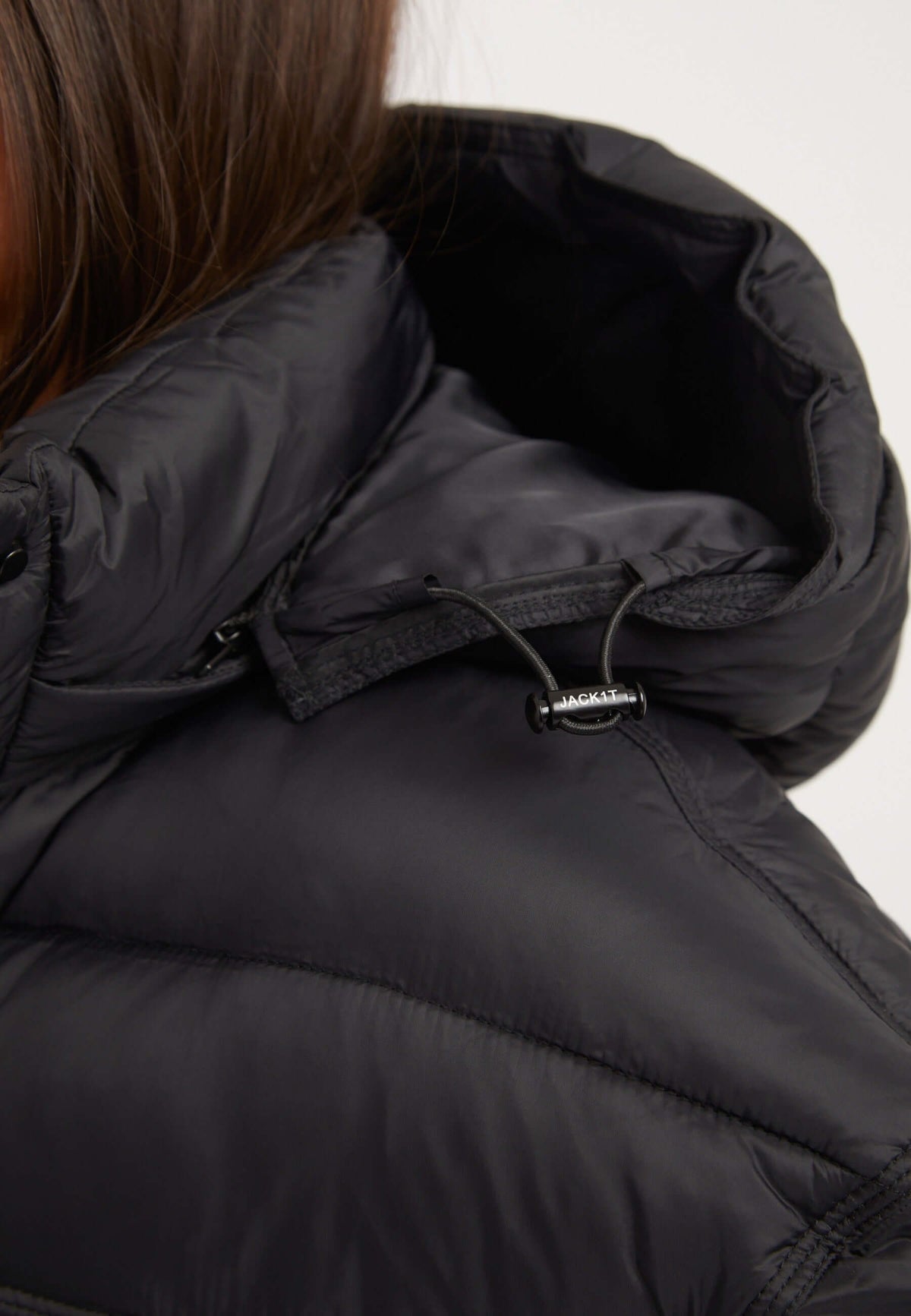 Close-up of the removable hood and detail of the womens black puffer jacket in black fabric.