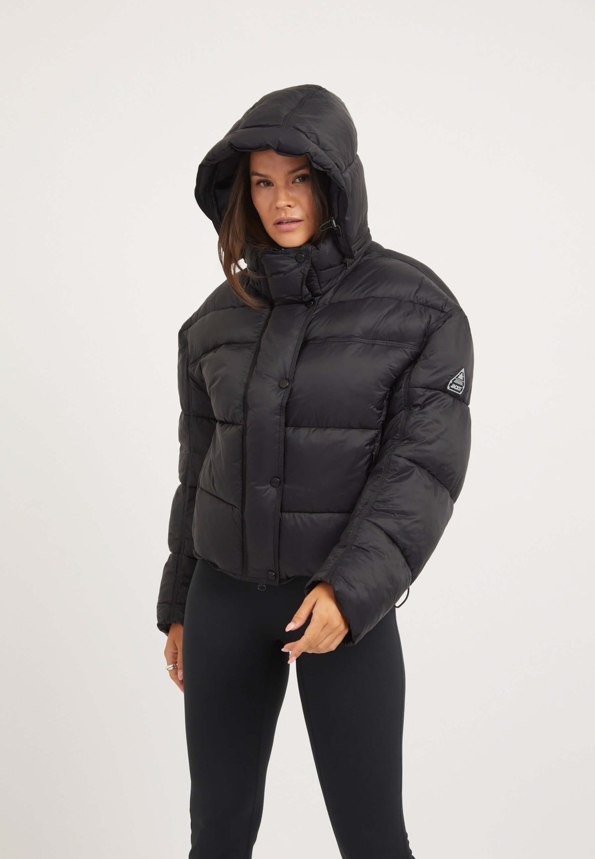 womens black puffer jacket worn by a model with hood and drop shoulder silhouette