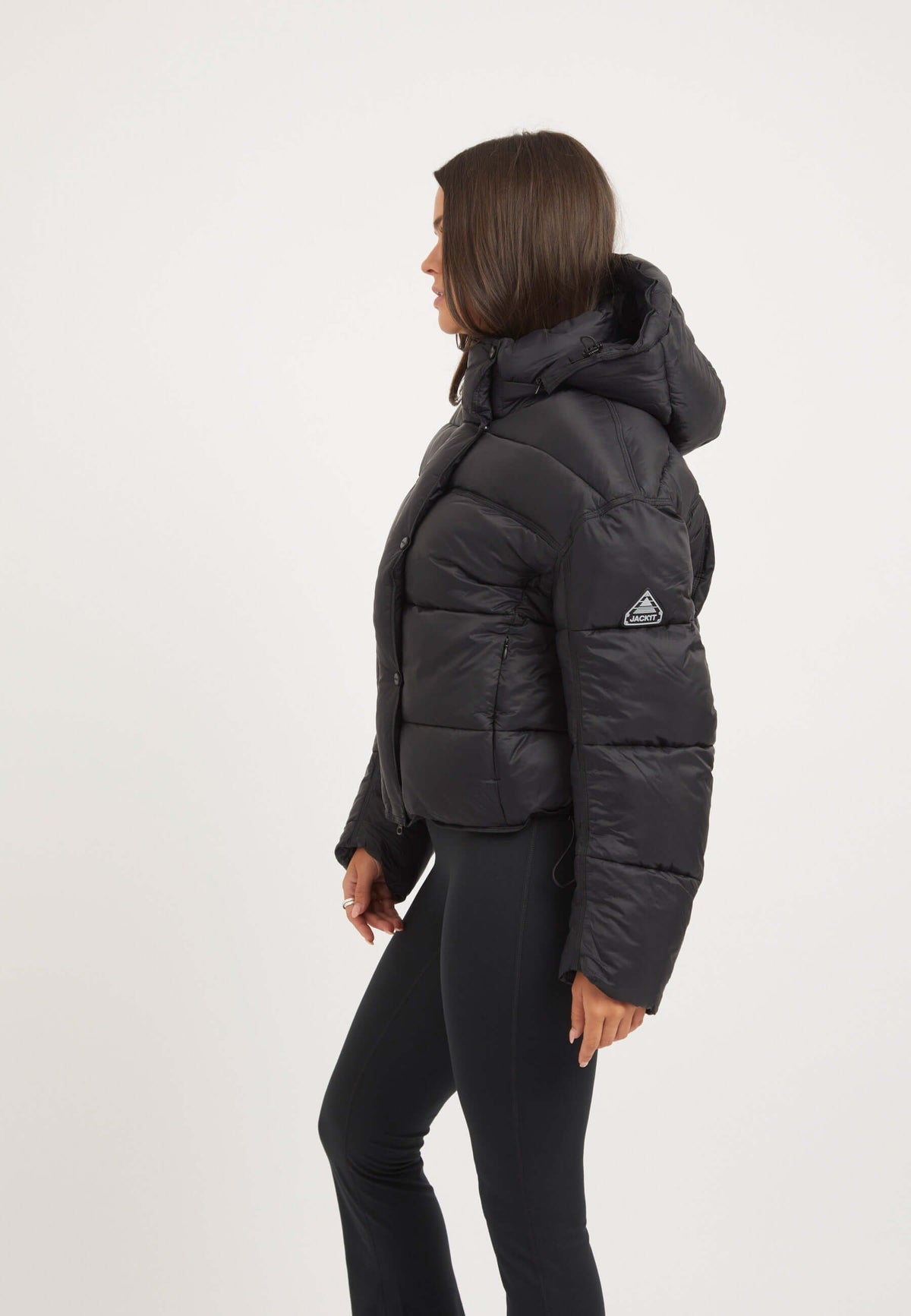 Womens black puffer jacket worn by model, showcasing oversized drop shoulder style and removable hood.