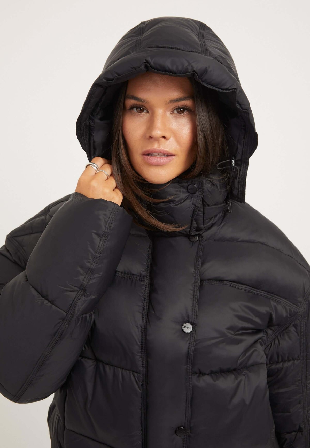 Model wearing a womens black puffer jacket with a hood, showcasing its oversized design and premium insulation.