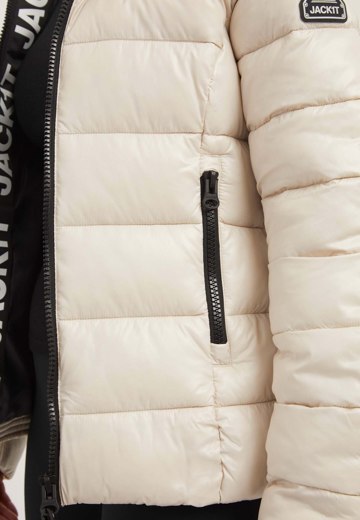 Close-up of R3D Slick Racer Jacket in Stone, showcasing its zip pocket and puffer design. Perfect womens racer puffer.