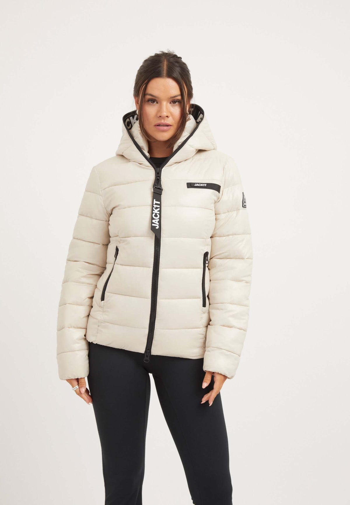 Womens racer puffer jacket in stone color with hood, tapered fit, and elasticated cuffs for winter style.