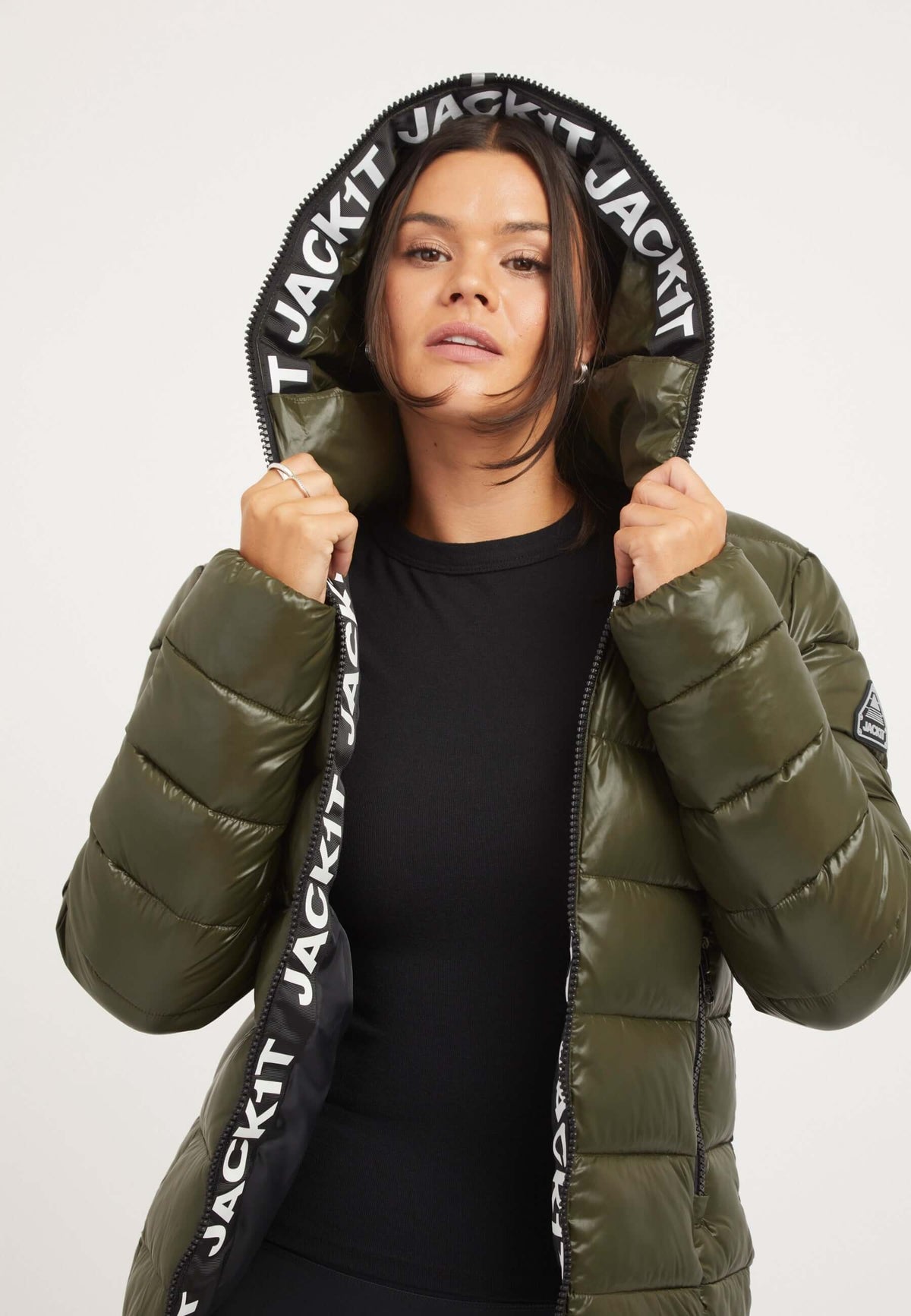 Woman wearing R3D Slick Racer Jacket Olive, a fitted puffer jacket with a stylish hood and zip.