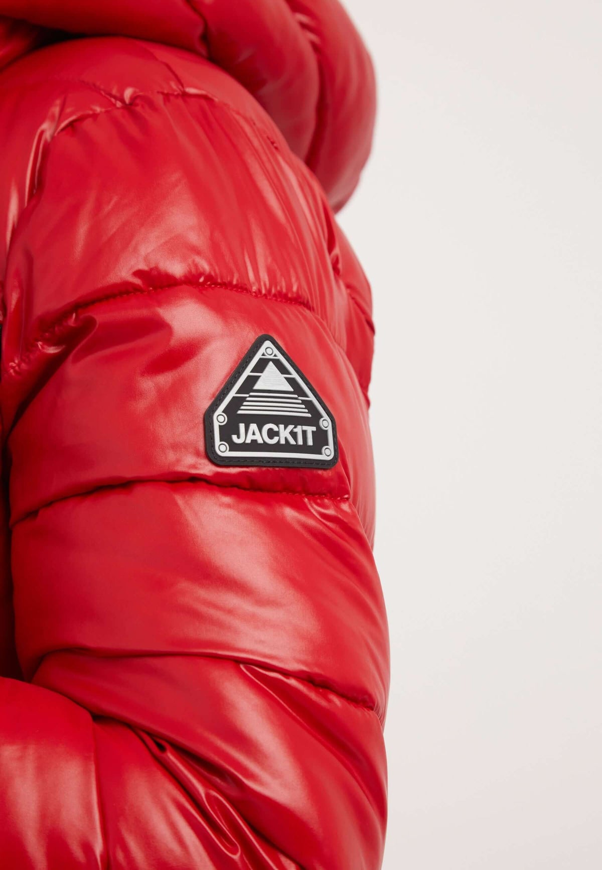 Close-up of R3D Slick Racer Jacket in cherry red showcasing the reflective badge and puffy texture of the short red jacket.