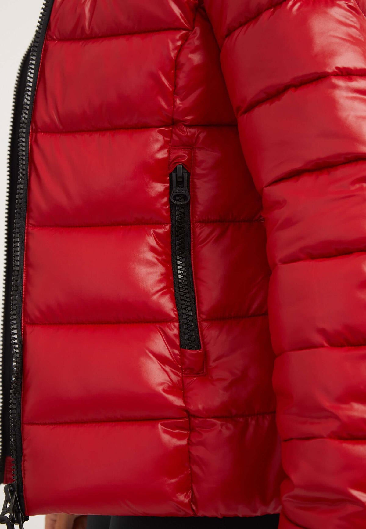 Close-up of a short red jacket featuring a zippered pocket and padded design.