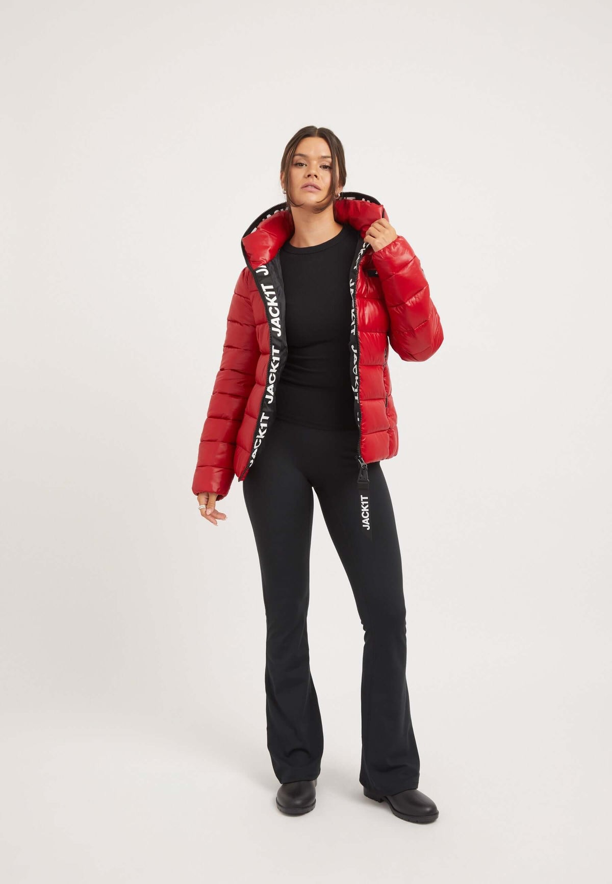 Model wearing a short red jacket with a tapered fit, showcasing padded design and elasticated cuffs, ideal for outdoor activities.