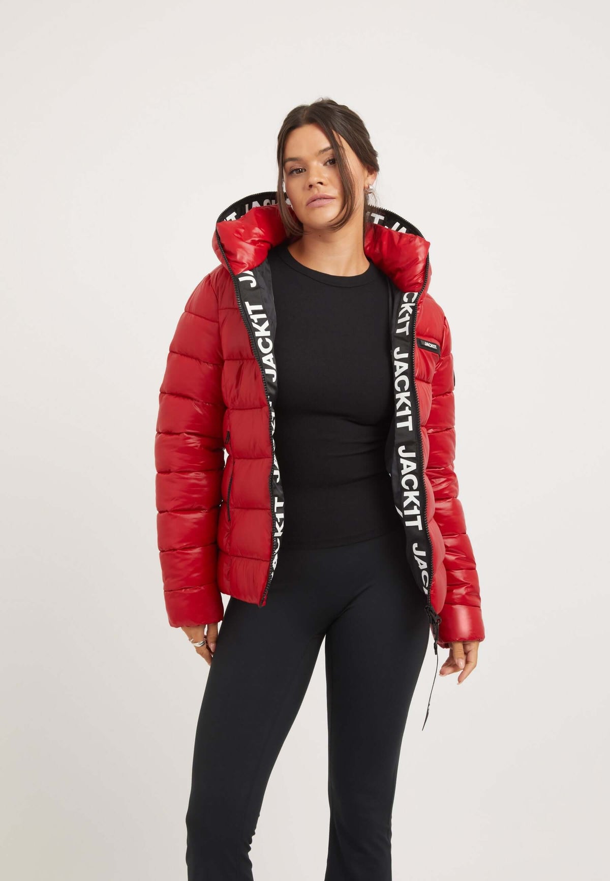 Short red jacket on model featuring a hood and elasticated waist, styled with black leggings.